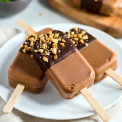 Here, I will break down the key ingredients for making Chocolate Peanut Butter Fudge Pops. Each item plays a role in creating a rich and creamy treat. - Peanut Butter: Use 1 cup of creamy peanut butter. It gives a smooth texture and rich flavor. - Coconut Milk: You need 1 cup of coconut milk or any milk you prefer. This adds creaminess. - Sweeteners: Use 1/2 cup of maple syrup or honey. This sweetens the pops and balances the cocoa. - Cocoa Powder: Include 1/2 cup of cocoa powder. This adds the deep chocolate flavor we love. - Flavorings and Salt: You will need 1 teaspoon of vanilla extract and 1/4 teaspoon of salt. The vanilla enhances the taste, while salt brings out the sweetness. - Optional Add-ins: If you want, add 1/2 cup of dark chocolate chips. They melt into the mix, adding extra richness and chocolate joy. These ingredients combine to create a delicious treat that is hard to resist. Each one plays a part in making these fudge pops a perfect dessert. {{ingredient_image_1}} - Heating the Peanut Butter and Coconut Milk Start by taking a medium saucepan. Add 1 cup of creamy peanut butter and 1 cup of coconut milk. Heat this over low-medium heat. Stir constantly. You want it to become smooth and creamy. Take your time; this step is key for a great texture. - Incorporating Sweeteners and Cocoa Once the mixture is smooth, remove it from the heat. Stir in 1/2 cup of maple syrup. Add 1/2 cup of cocoa powder as well. Next, add 1 teaspoon of vanilla extract and 1/4 teaspoon of salt. Mix well until everything is combined. This adds sweetness and depth of flavor. - Adding Flavorings and Optional Chocolate Chips If you like extra chocolate, fold in 1/2 cup of dark chocolate chips. Make sure they melt into the mixture. This step is optional, but it makes the fudge pops richer and more decadent. - Transferring Mixture to Molds Let the mixture cool slightly. After that, pour it into your popsicle molds. Leave some space at the top of each mold. This space allows for expansion when freezing. - Inserting Sticks Carefully insert sticks into the molds. Make sure they stand straight. This will help you enjoy the pops later. - Freezing Time and Tips Place the molds in the freezer. Freeze for at least 4-6 hours. Wait until they are completely solid. If you want them to freeze faster, place them toward the back of the freezer. - Techniques to Remove Pops from Molds To release the fudge pops, run warm water over the outside of the molds. This helps loosen them. You can also gently wiggle the sticks. This can help pop them out without breaking. - Presentation Tips for Serving Serve the fudge pops on a nice plate. Drizzle melted chocolate over them for a fancy touch. You can also sprinkle crushed peanuts on top for added crunch. This makes them look even more delicious! - Overheating Ingredients Heating the peanut butter and coconut milk too fast can ruin the mix. Keep the heat low and stir often. This way, you’ll keep the texture smooth and creamy. - Not Allowing Enough Freezing Time If you pull the pops too soon, they may be mushy. Freeze them for at least 4-6 hours. This ensures they are solid and ready to enjoy. - Adding Nuts or Toppings You can make your fudge pops even better by adding nuts. Chopped peanuts or almonds give a nice crunch. You can also sprinkle toppings like crushed cookies or sea salt. - Adjusting Sweetness to Taste Everyone has different sweetness levels. Taste the mix before freezing. If you want it sweeter, add a bit more maple syrup or honey. - Best Popsicle Molds to Use Silicone molds work great for easy removal. They let you pop the fudge out with ease. Look for molds with fun shapes to make them even more exciting. - Tools for Mixing and Heating Use a medium saucepan for heating. A whisk helps mix the ingredients smoothly. A rubber spatula is great for scraping every bit into the molds. Pro Tips Use Room Temperature Ingredients: Let your peanut butter and coconut milk come to room temperature before mixing. This helps them blend more smoothly and evenly. Experiment with Sweeteners: Feel free to adjust the sweetness to your liking by adding more or less maple syrup or honey, depending on your taste preference. Customize with Mix-ins: Add your favorite nuts, dried fruits, or even a pinch of sea salt to the mixture before freezing for a unique twist. Store Properly: To keep your fudge pops fresh, wrap them individually in plastic wrap or store them in an airtight container in the freezer. {{image_2}} Dairy-Free Options You can easily make this treat dairy-free. Use coconut milk as I suggest, or try almond milk. Both options keep the fudge pops creamy and rich. They add nice flavors too. Nut Milk Suggestions If you prefer nut milk, cashew or hazelnut milk works well. These milks add a unique taste to the fudge. Remember, always check for allergies when using nut milks. Adding Mint Extract For a refreshing twist, add a few drops of mint extract. It brings a cool flavor that pairs great with chocolate. Just a little goes a long way, so start small. Swapping Cocoa for Flavored Powders Try using flavored powders instead of cocoa. You can swap in matcha or chai powder for a fun change. This gives your fudge pops a new look and taste. Vegan and Low-Sugar Options To make these fudge pops vegan, stick with maple syrup. It’s a great sweetener that keeps everything plant-based. You can also cut back on the syrup for a low-sugar version. Nut-Free Alternatives If you need nut-free options, replace peanut butter with sunbutter. This will still give you that creamy texture. It’s safe for schools and nut-free zones too. To keep your fudge pops fresh, follow these simple steps: - Best Practices for Freezing: Make sure your pops are fully frozen before storage. This helps prevent ice crystals. Store them in the back of the freezer where it's coldest. - Container Recommendations: Use airtight containers or freezer bags. Label each bag with the date. This helps you track freshness. If using containers, choose ones that fit the pops well to save space. Understanding how long your fudge pops last is key. - How Long Do They Last? Frozen fudge pops can last up to three months. After this, they may lose flavor or texture. - Signs of Spoilage: Look for ice crystals on the surface or a change in color. If the texture feels grainy, it's best to toss them. Always trust your senses; if something seems off, it likely is. Yes, you can use different sweeteners. Agave syrup or stevia are great options. They add sweetness without using sugar. Adjust the amount based on your taste. For example, use less stevia since it is sweeter than sugar. Maple syrup is also a good choice if you want a natural flavor. Just remember, each sweetener may change the taste a bit. No worries if you lack popsicle molds! You can use small cups instead. Just fill them with the mixture and insert a stick. Ice cube trays work well too. Each cube will be a mini pop! You can also use muffin tins for larger pops. Just be sure to cover them with plastic wrap to hold the sticks in place. Absolutely! You can make these fudge pops in advance. They freeze well for up to two weeks. Just store them in an airtight container. Take them out when you want a treat. This makes them perfect for parties or hot days. Prepare them ahead, and enjoy a cool delight whenever you want! Making fudge pops is fun and easy. We covered ingredients, steps, tips, and variations. Start with peanut butter, coconut milk, and cocoa. Heat and mix them, then freeze for tasty treats. Avoid common mistakes and try different flavors. These fudge pops fit many diets and preferences. With the right storage, they last a long time. Enjoy creating your own version, and share it with friends and family for a delightful snack.